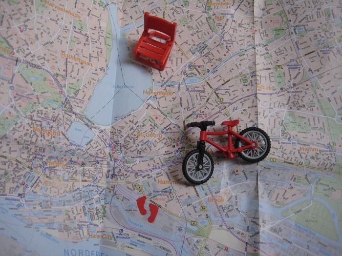 Foto Rundgang Hamburg: Miniatur-Fahrrad, -Klappstuhl, -Fußspuren auf Stadtplan. Fotografin: Maren Cornils